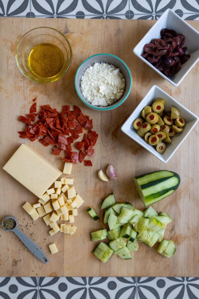 overhead shot of ingredients for road trip pasta salad laid out on a wooden surface
