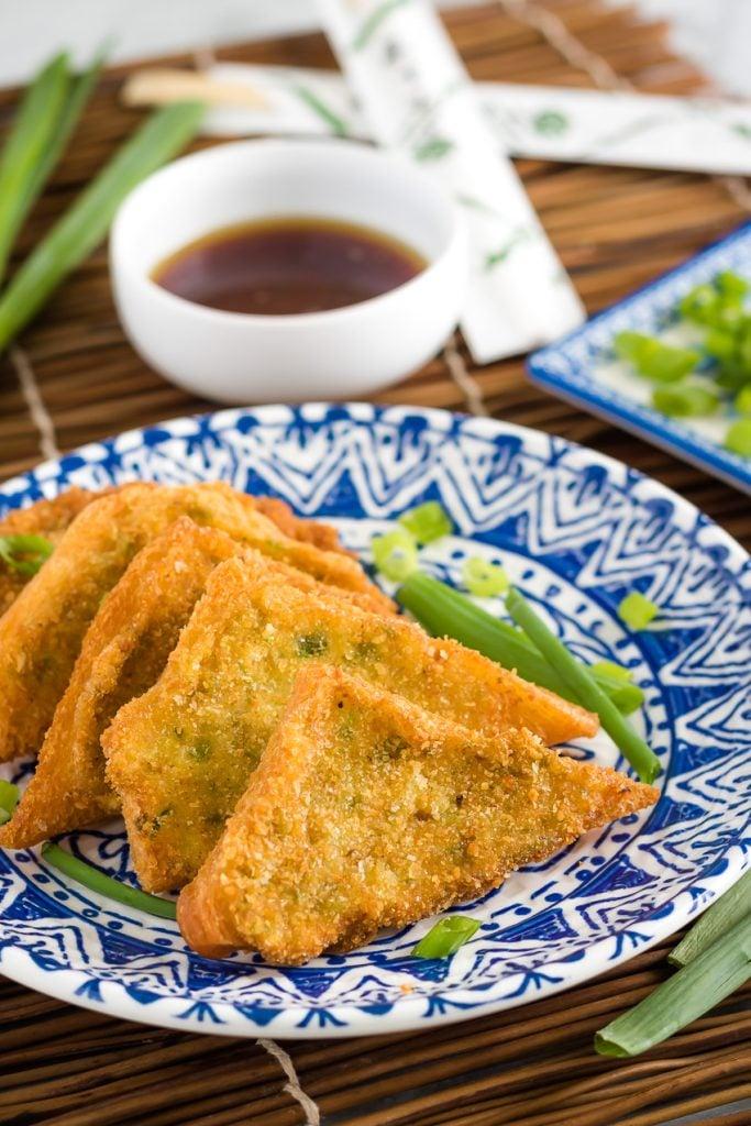 Hands spreading shrimp paste onto white bread slices, ready for sesame coating