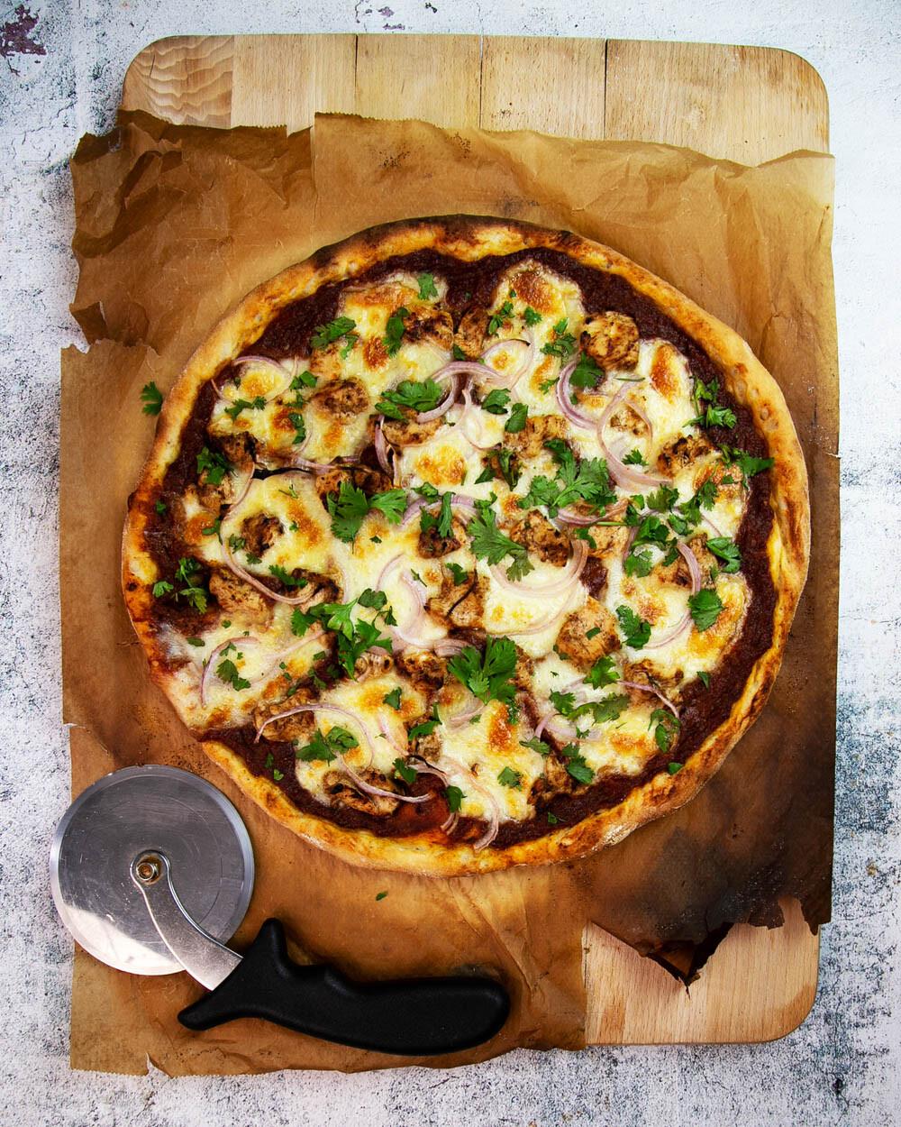 Chicken Korma Pizza Bianco on a wooden pizza peel