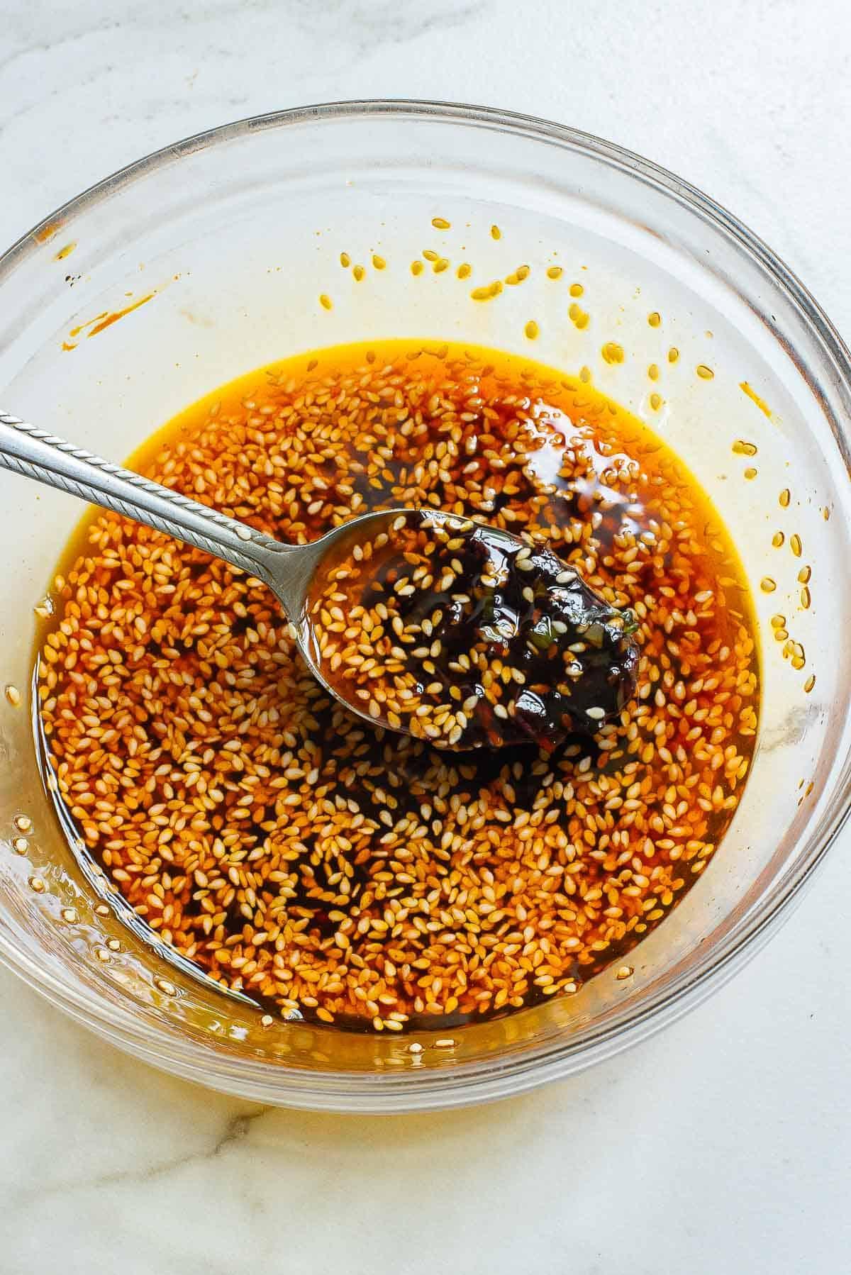 Close up of a bowl of vibrant chili oil with visible chili flakes and garlic