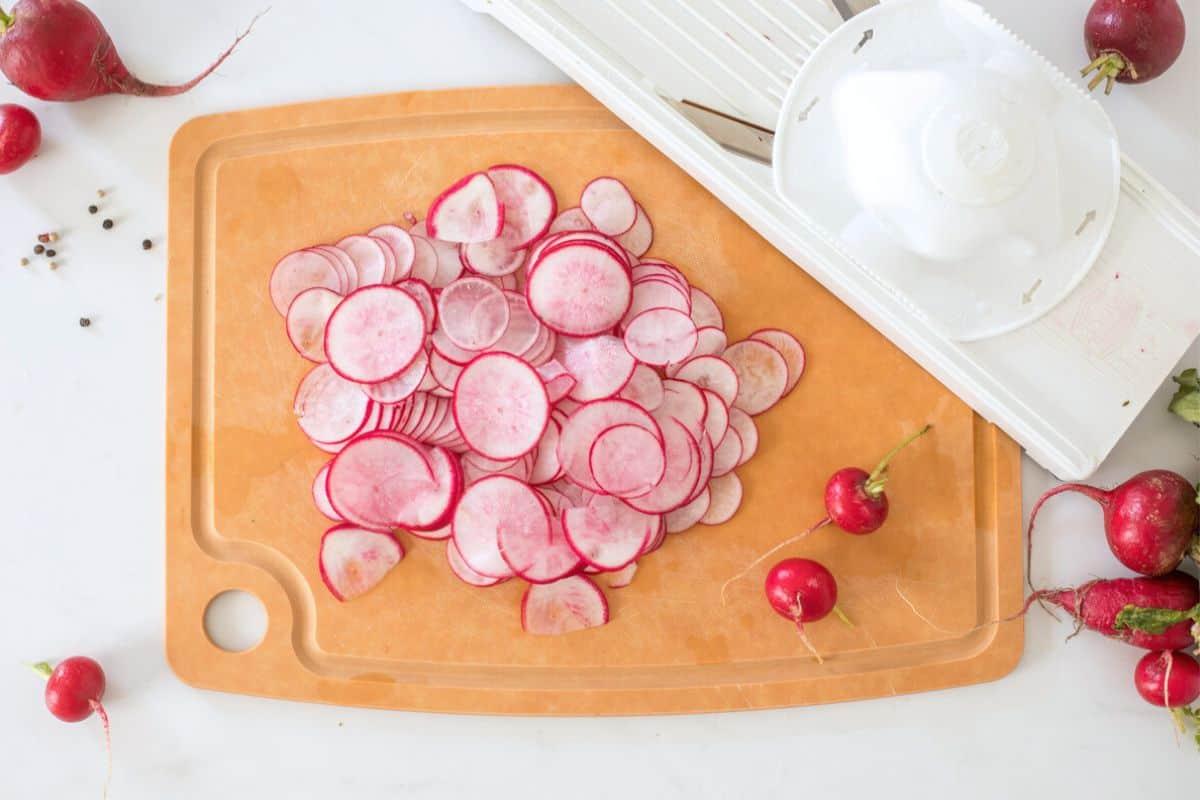 Ingredients for quick pickled radishes on a wooden cutting board