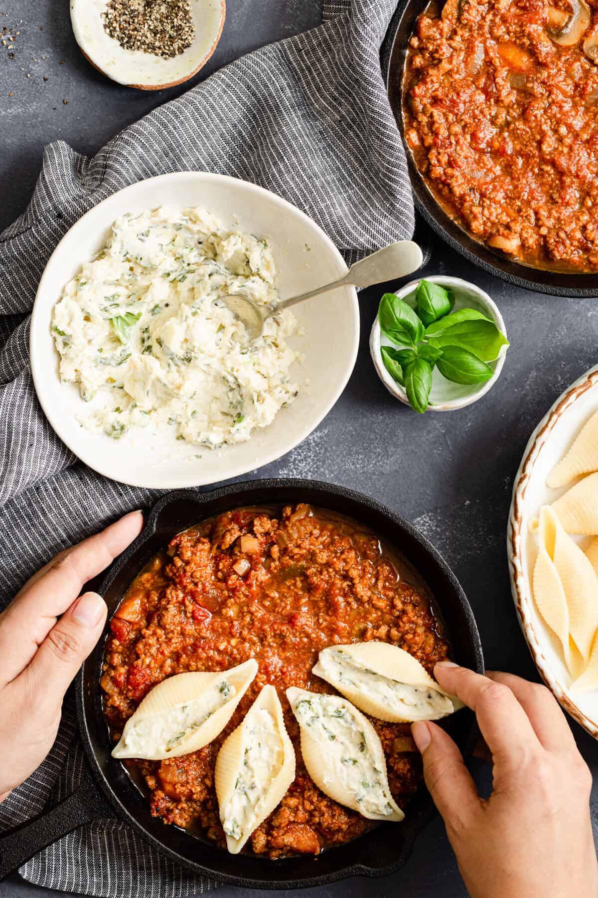 stuffed pasta shells being arranged in a baking dish