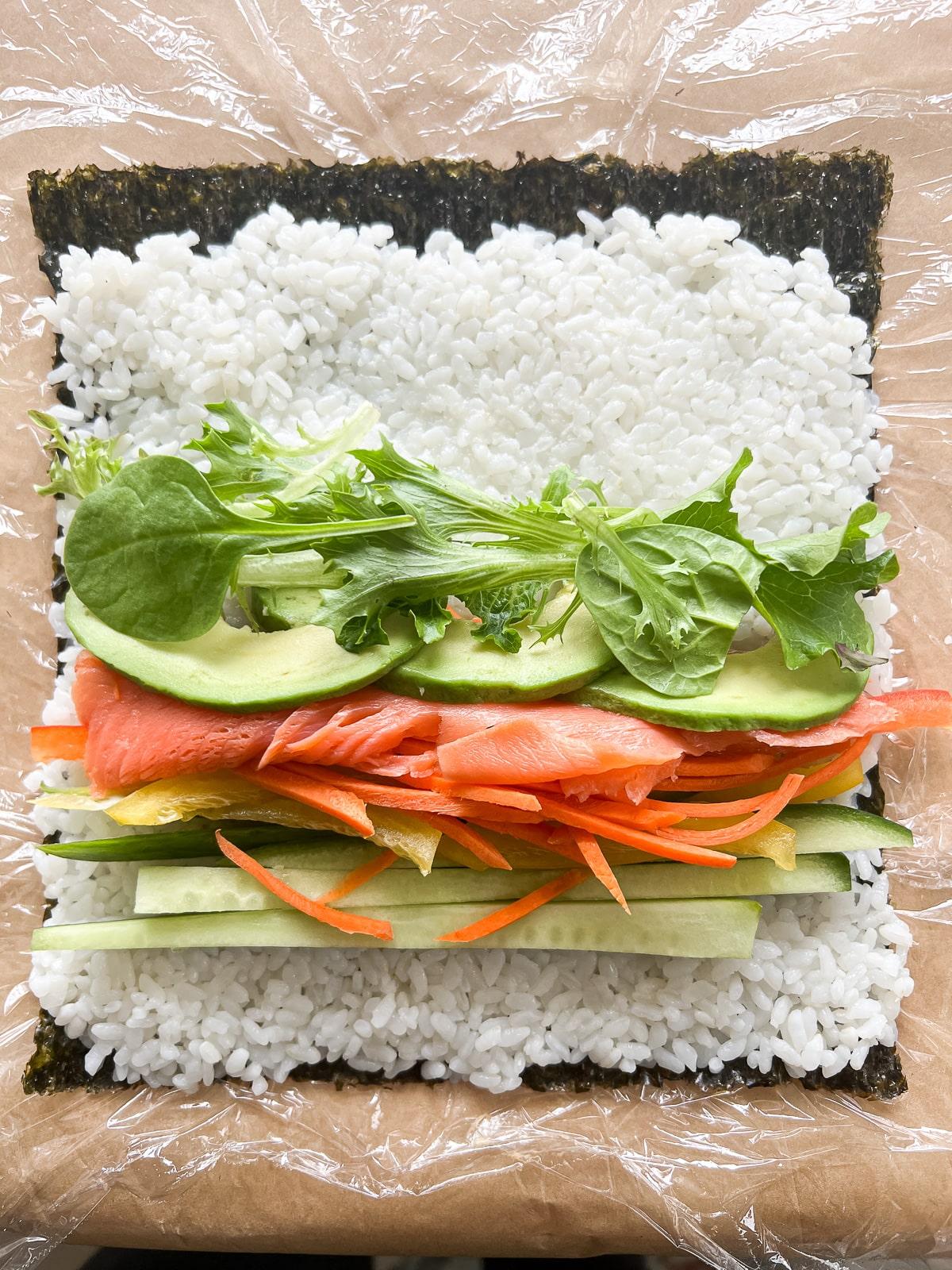 a close-up shot of a sushi burrito being cut in half, revealing the colorful fillings