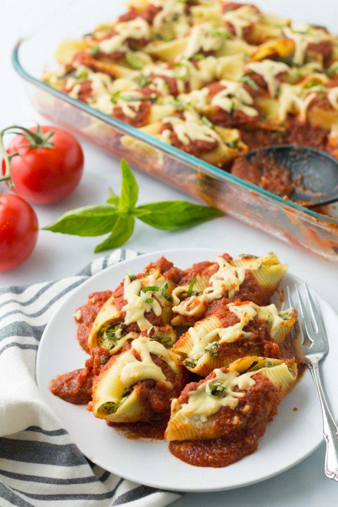 A serving of Tofu and Spinach Stuffed Shells on a plate, garnished with fresh basil leaves