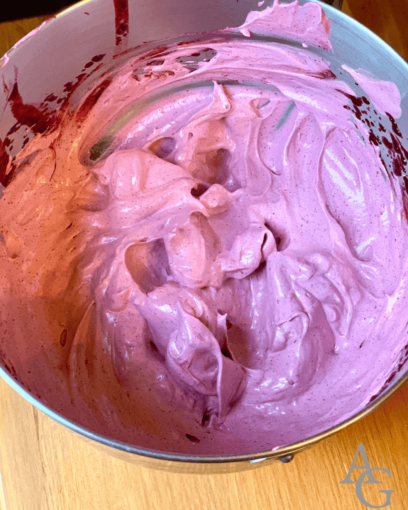 A person folding whipped cream into lingonberry mixture.
