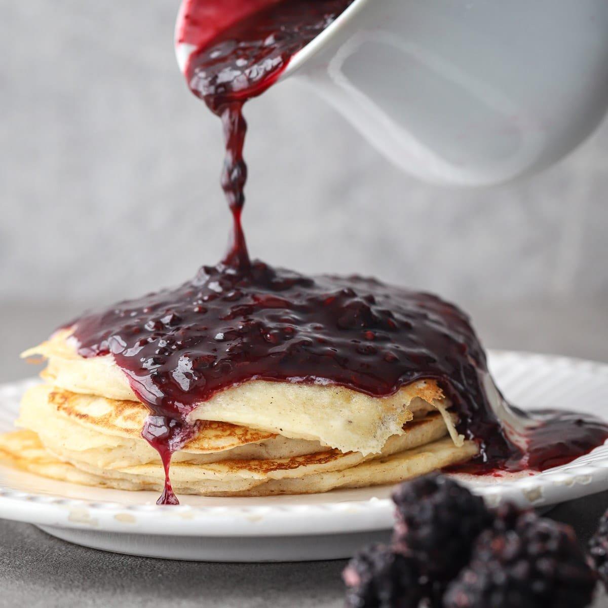 Blackberry rosemary syrup being poured over pancakes