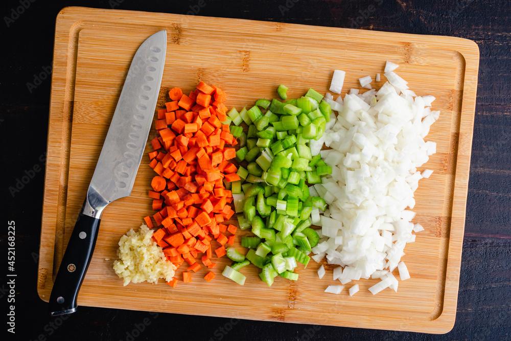 overhead shot of various vegetable scraps (carrot peels, broccoli stems, onion ends) arranged neatly on a wooden cutting board