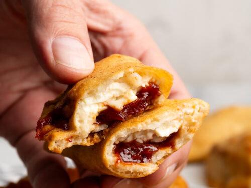 Close-up shot of a single guava and cheese empanada, showing the flaky crust and oozing cheese filling