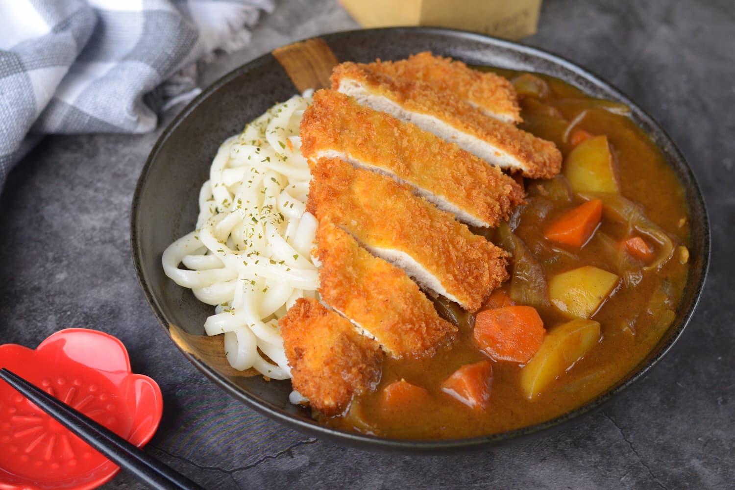 overhead shot of curry udon with crispy chicken katsu in a rustic bowl
