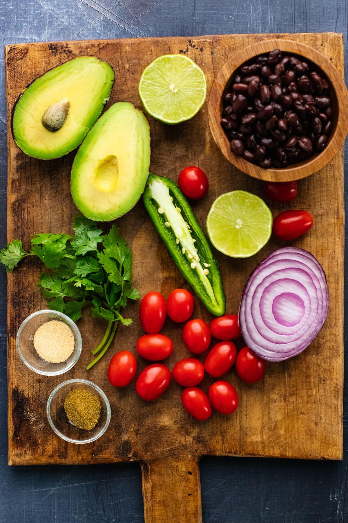 Ingredients for Anasazi bean and avocado salsa arranged on a wooden table