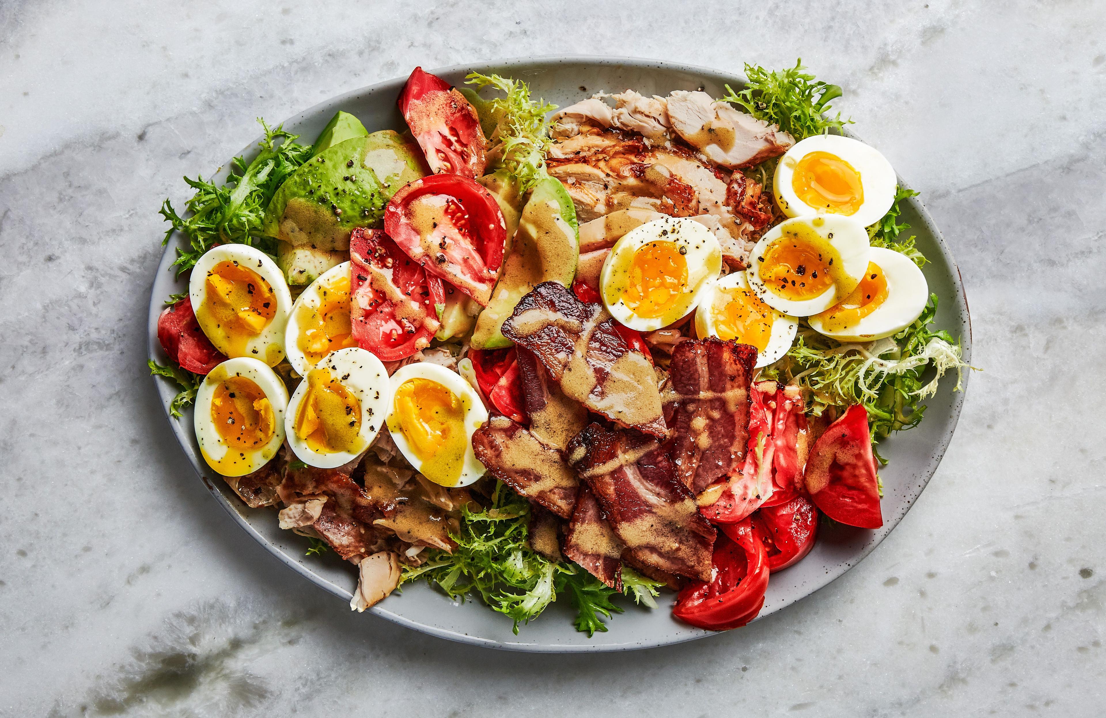 Hard-boiled egg and bacon Cobb salad on a rustic wooden table