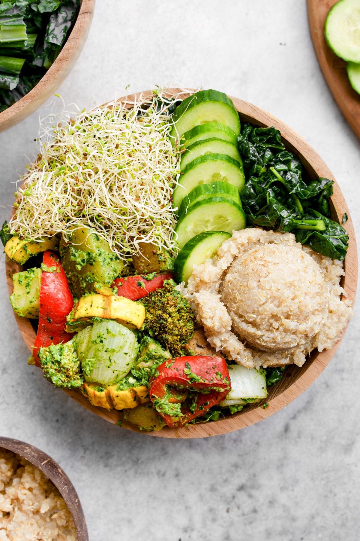 Ingredients for basil veggie bowl laid out on a wooden cutting board, colorful vegetables, fresh basil, quinoa