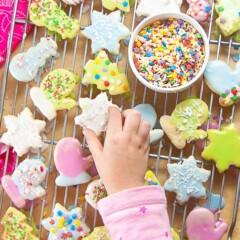 Child's hands decorating chocolate cookies with colorful icing and sprinkles, slightly messy