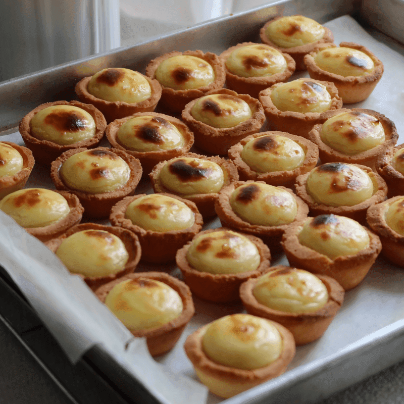 Close-up of golden brown mini cheese tarts with bubbly cheese filling on a cooling rack