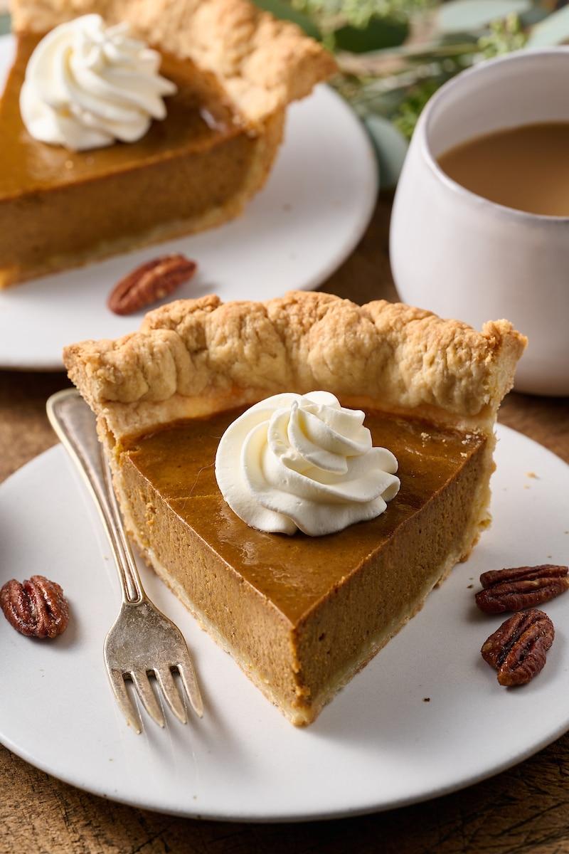 homemade creamy pumpkin pie with flaky butter crust, golden brown, served on a rustic wooden table with autumn decor