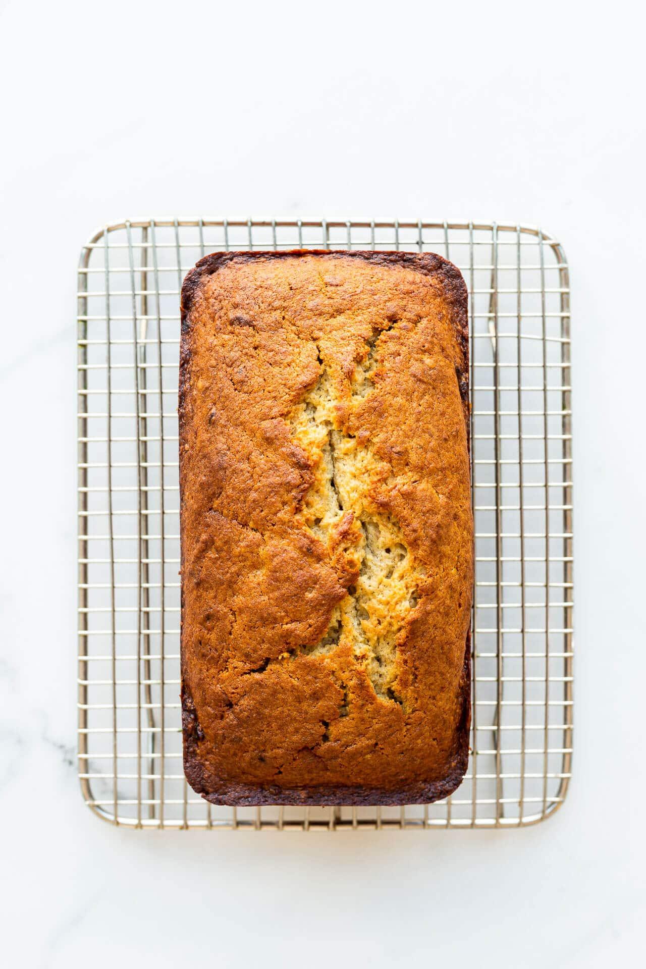 Freshly baked banana bread cooling on a wire rack with steam gently rising