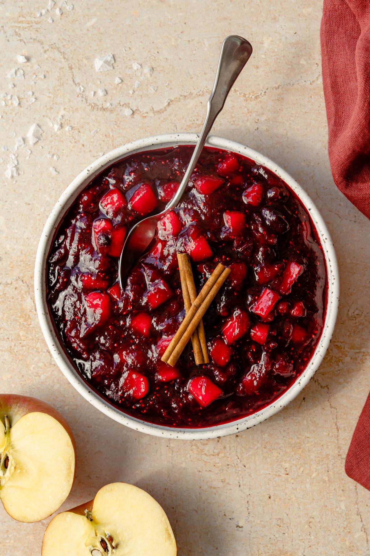 Close-up of bubbling cranberry apple sauce in a rustic saucepan on a stove, steam rising