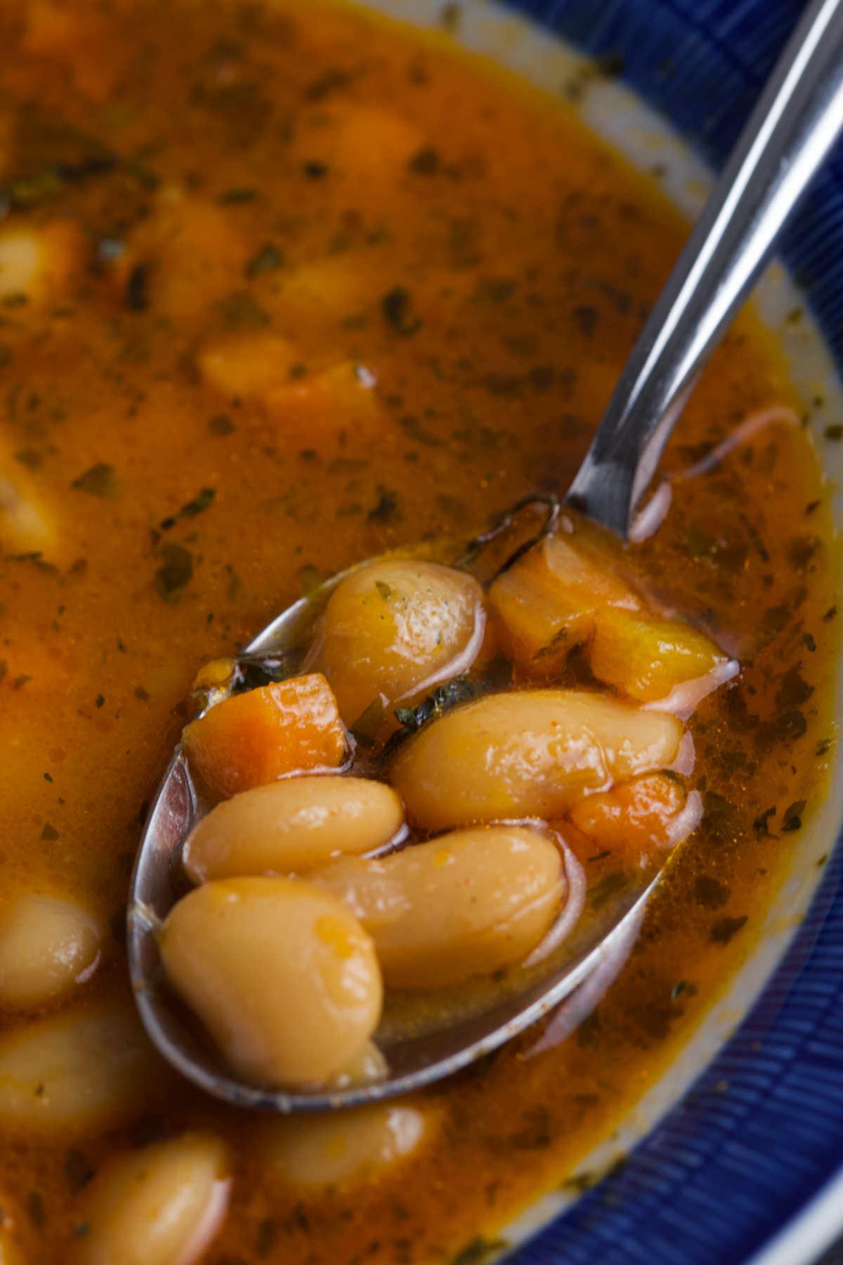 Close-up shot of a steaming bowl of sausage and white bean soup