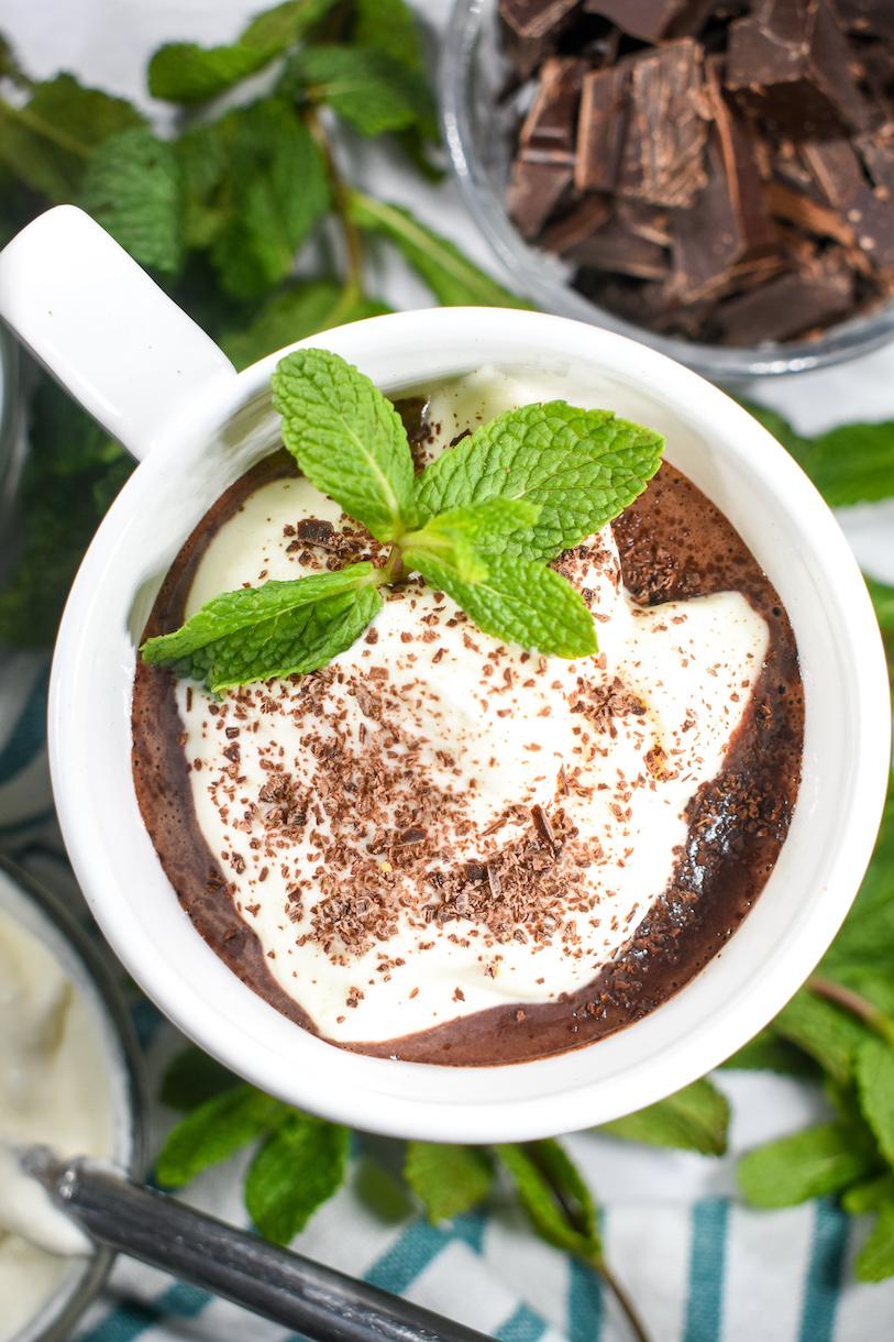 steaming mug of mint hot chocolate topped with whipped cream and chocolate shavings