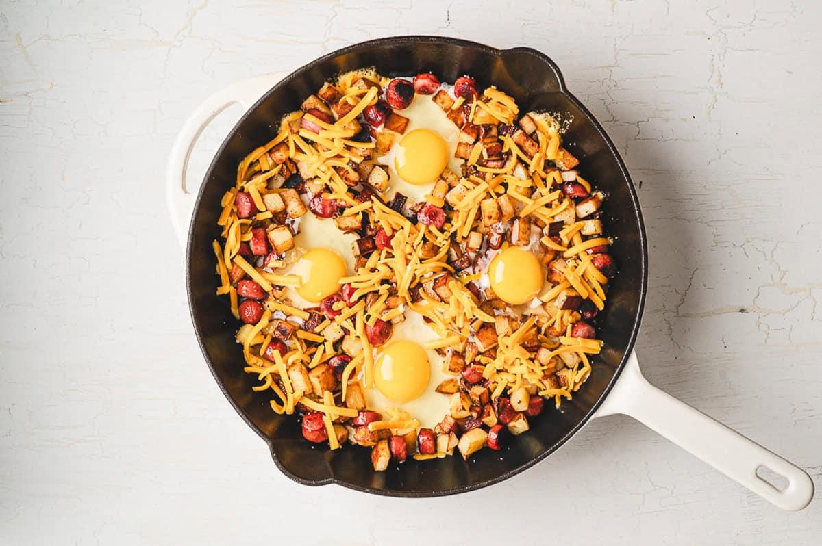 overhead shot of cast iron skillet with cooked egg-loaded hash before serving, steam rising