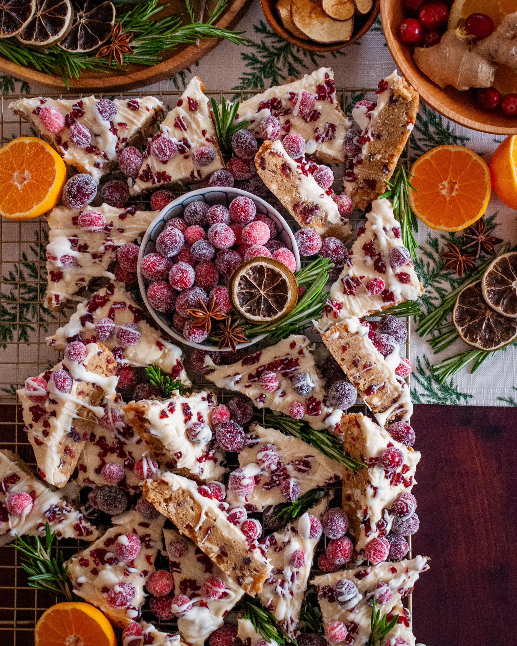 overhead shot of festive cranberry bliss bars with white cream cheese frosting, orange zest, and chopped cranberries