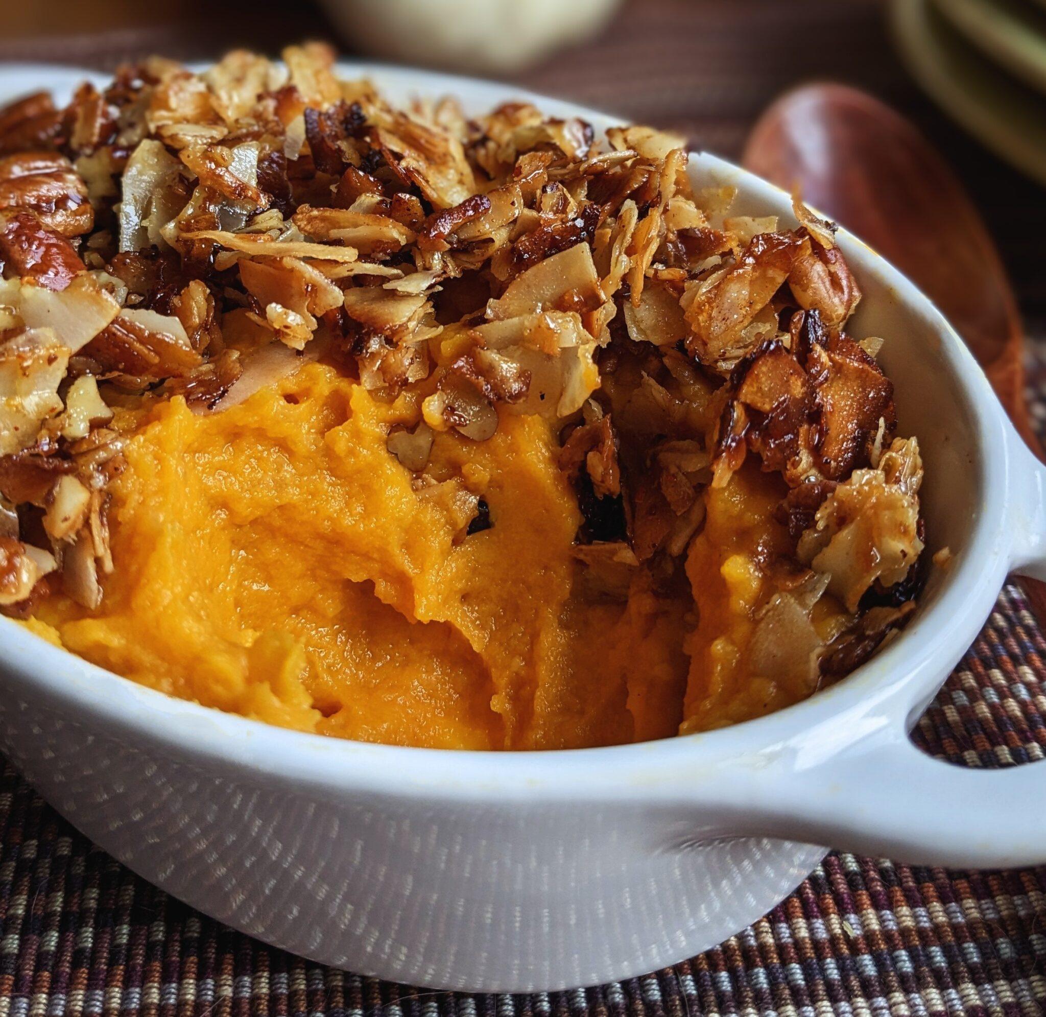 Warm sweet potato casserole dish on a rustic wooden table with a side of toasted coconut