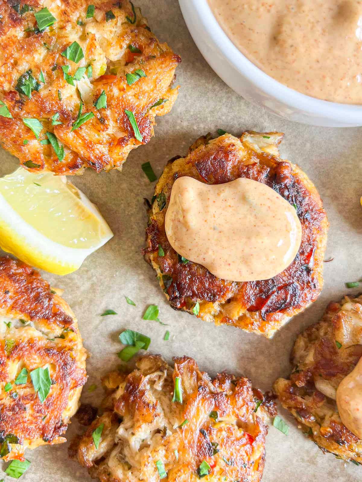 close-up shot of a perfectly sautéed crab cake with remoulade sauce drizzled over it