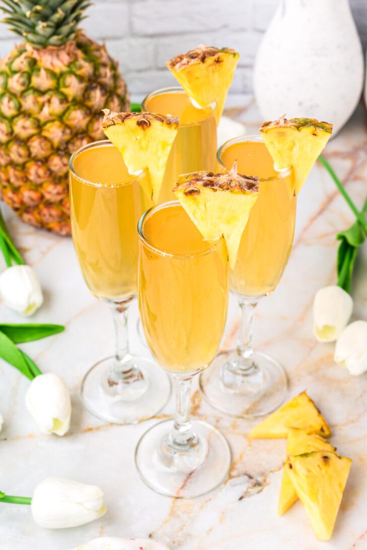 close up of a pineapple cilantro serrano mimosa being poured into a champagne flute