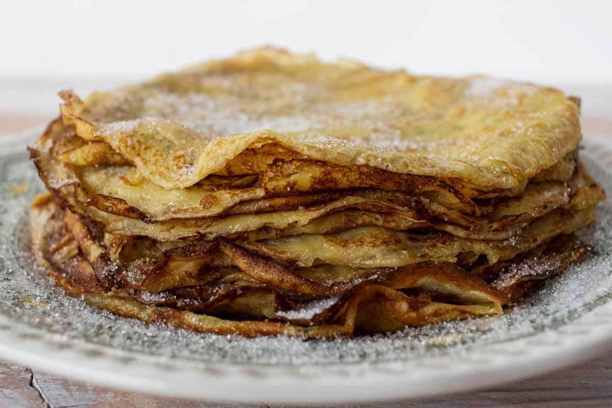A pan with frixuelos being cooked, showcasing the thin, crepe-like texture