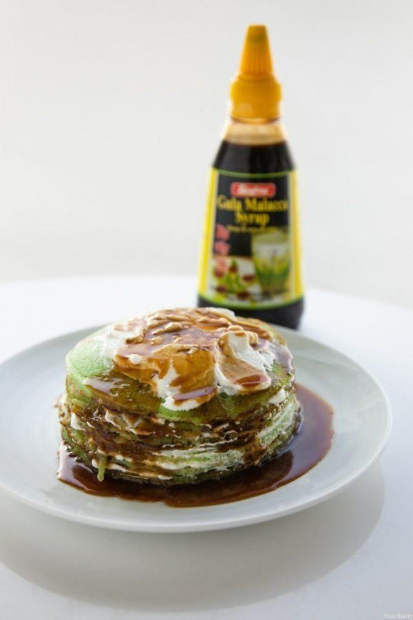 A stack of pandan pancakes being drizzled with gula melaka syrup