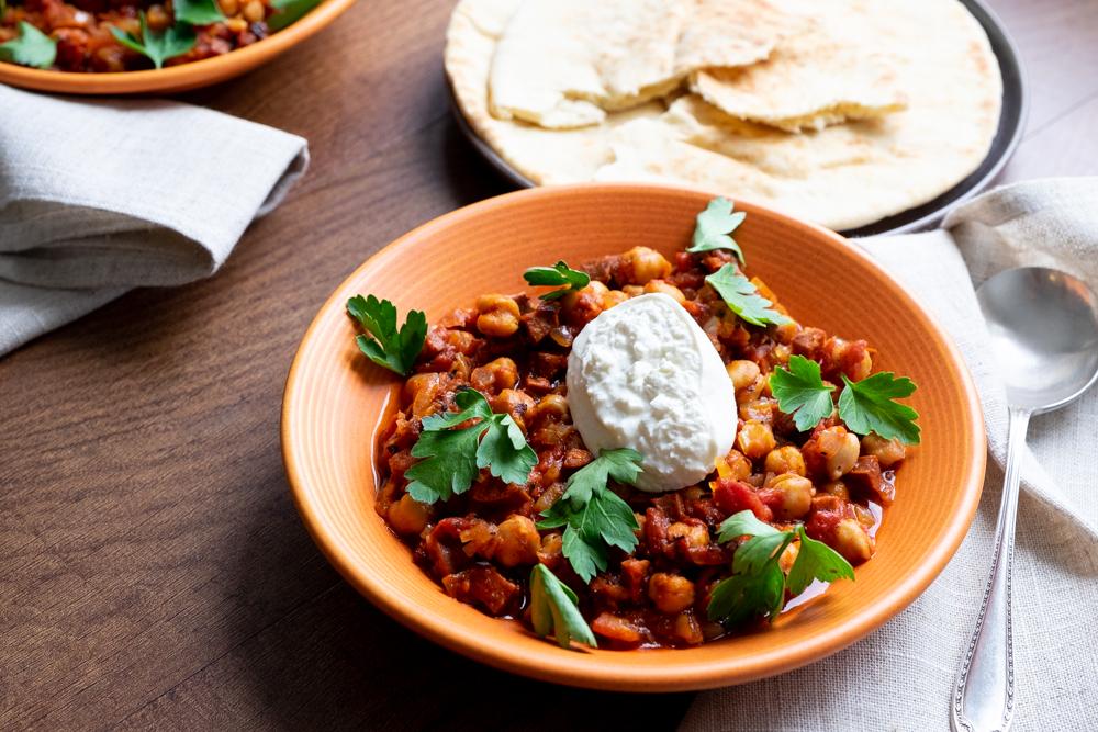 Slow cooker filled with spicy chorizo and chickpea chili topped with lime crema