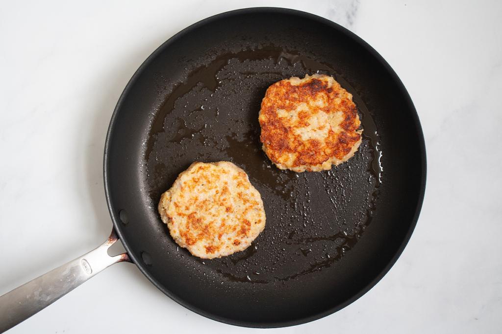 Close-up shot of the shrimp patties cooking in a skillet.