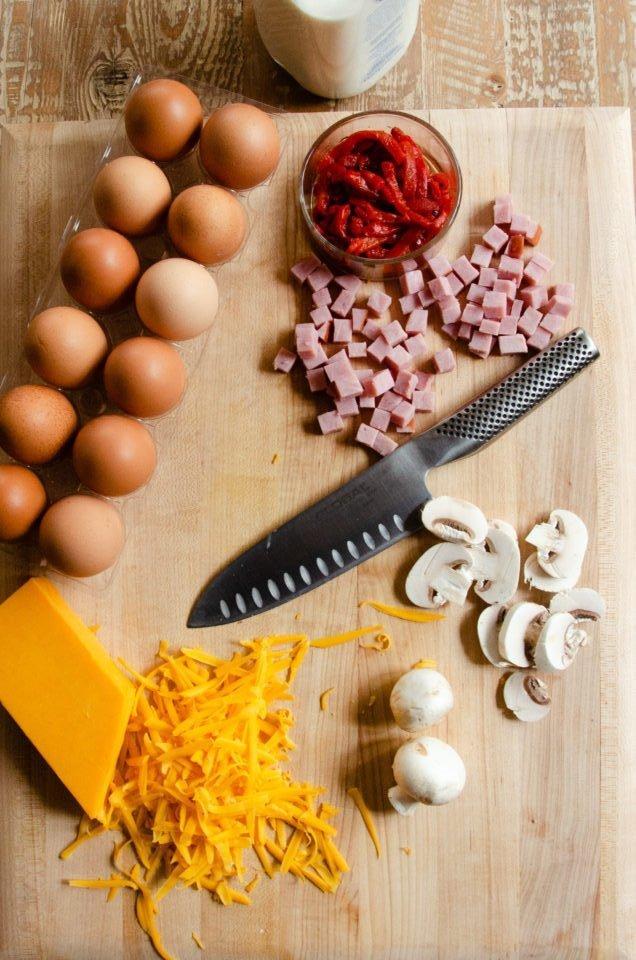 a person slicing and serving a frittata on a wooden cutting board