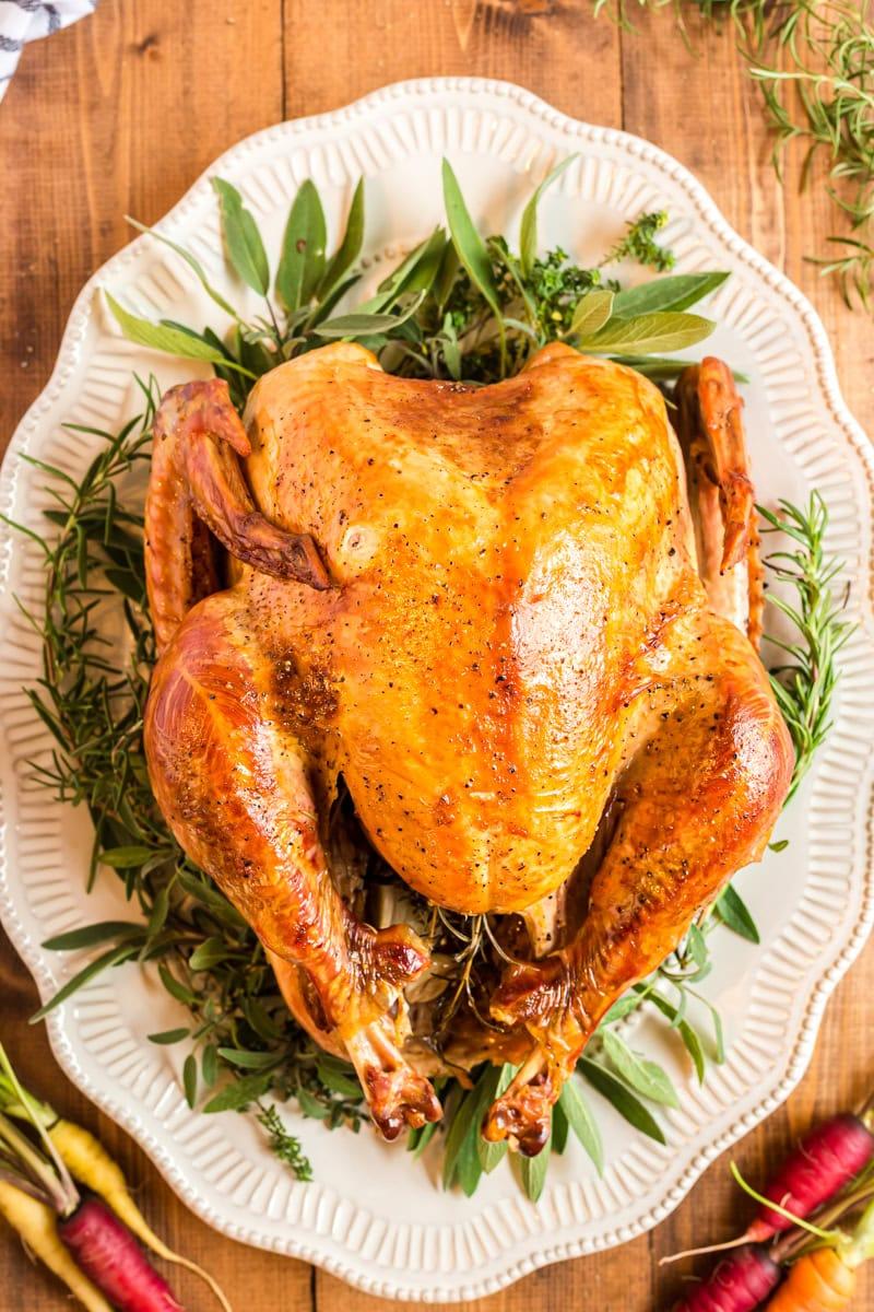 Close-up of a perfectly roasted turkey with crispy skin, garnished with fresh thyme and roasted garlic cloves on a festive platter