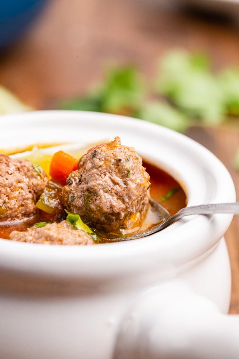 Close-up shot of a spoonful of keto albondigas soup, showcasing the meatballs and vegetables