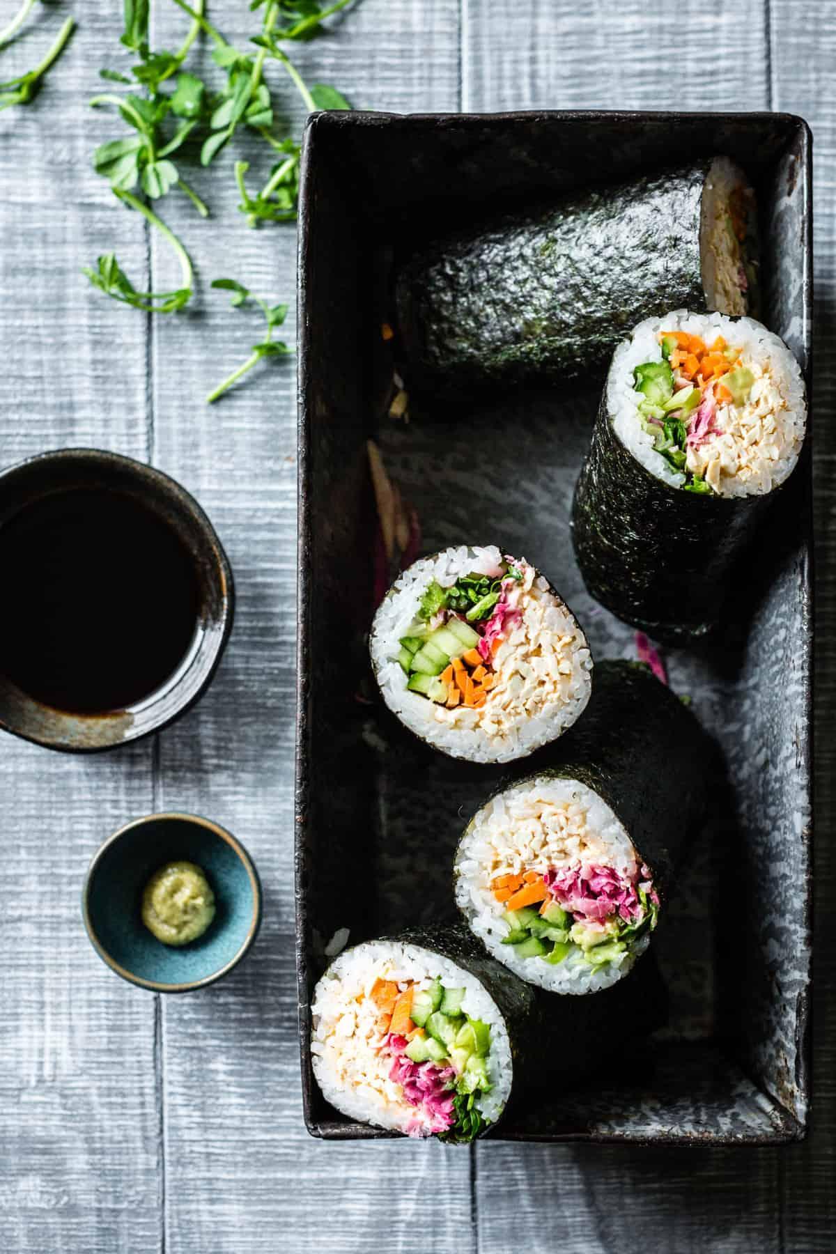 a person holding a sushi burrito while hiking in a scenic outdoor setting