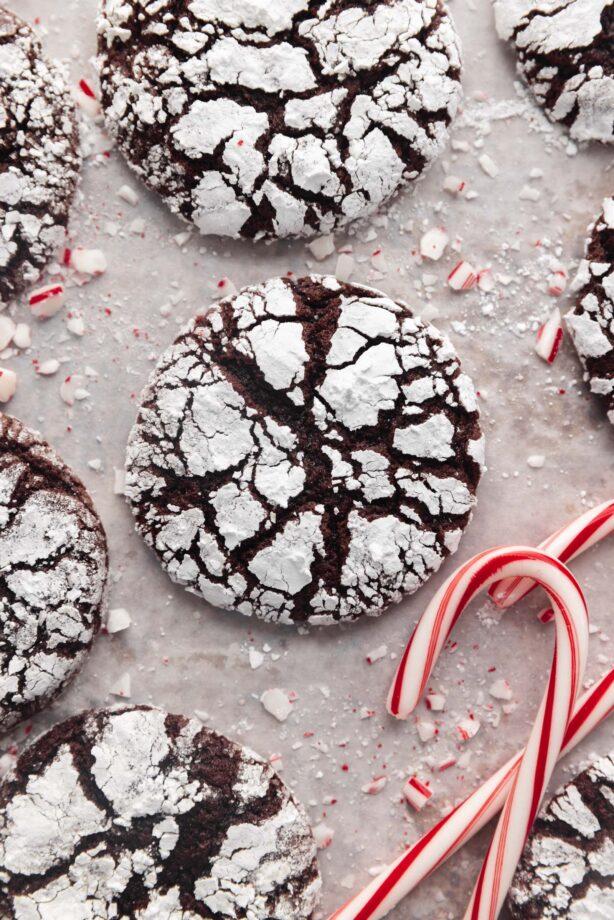 Close-up of peppermint crackle cookies baking in an oven, showing the cracks forming on the powdered sugar coating