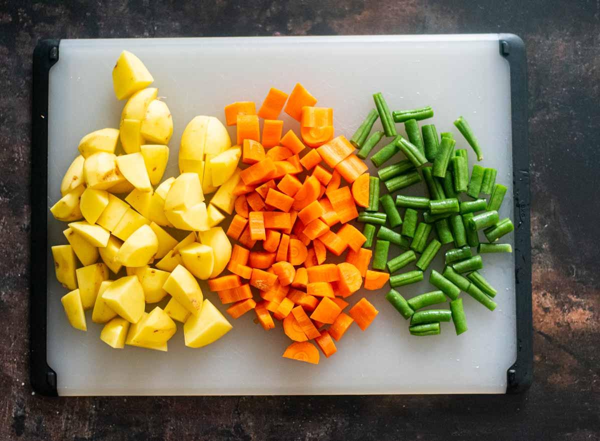 various fresh vegetables being chopped for stew
