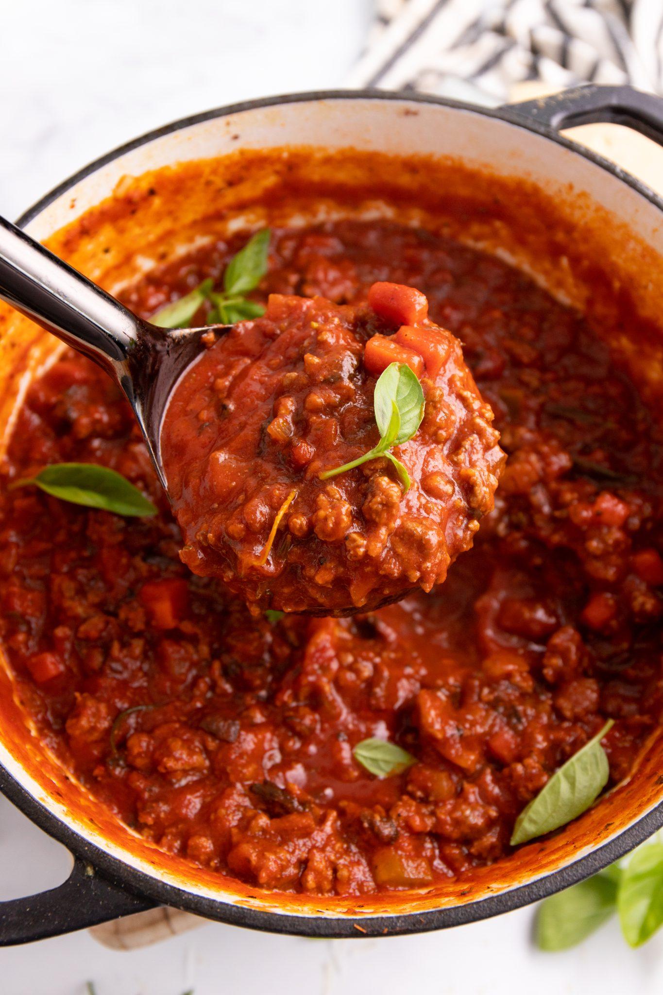 beef bolognese simmering in a dutch oven on a stove
