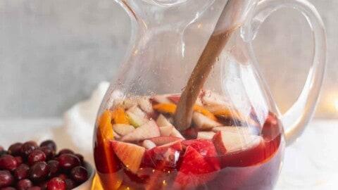vibrant ruby red sangria with fresh fruit and ice in a decorative pitcher, holiday setting