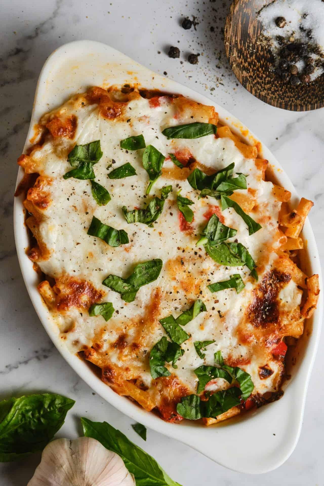 Close-up of baked ziti with melted mozzarella and ricotta, garnished with fresh basil leaves