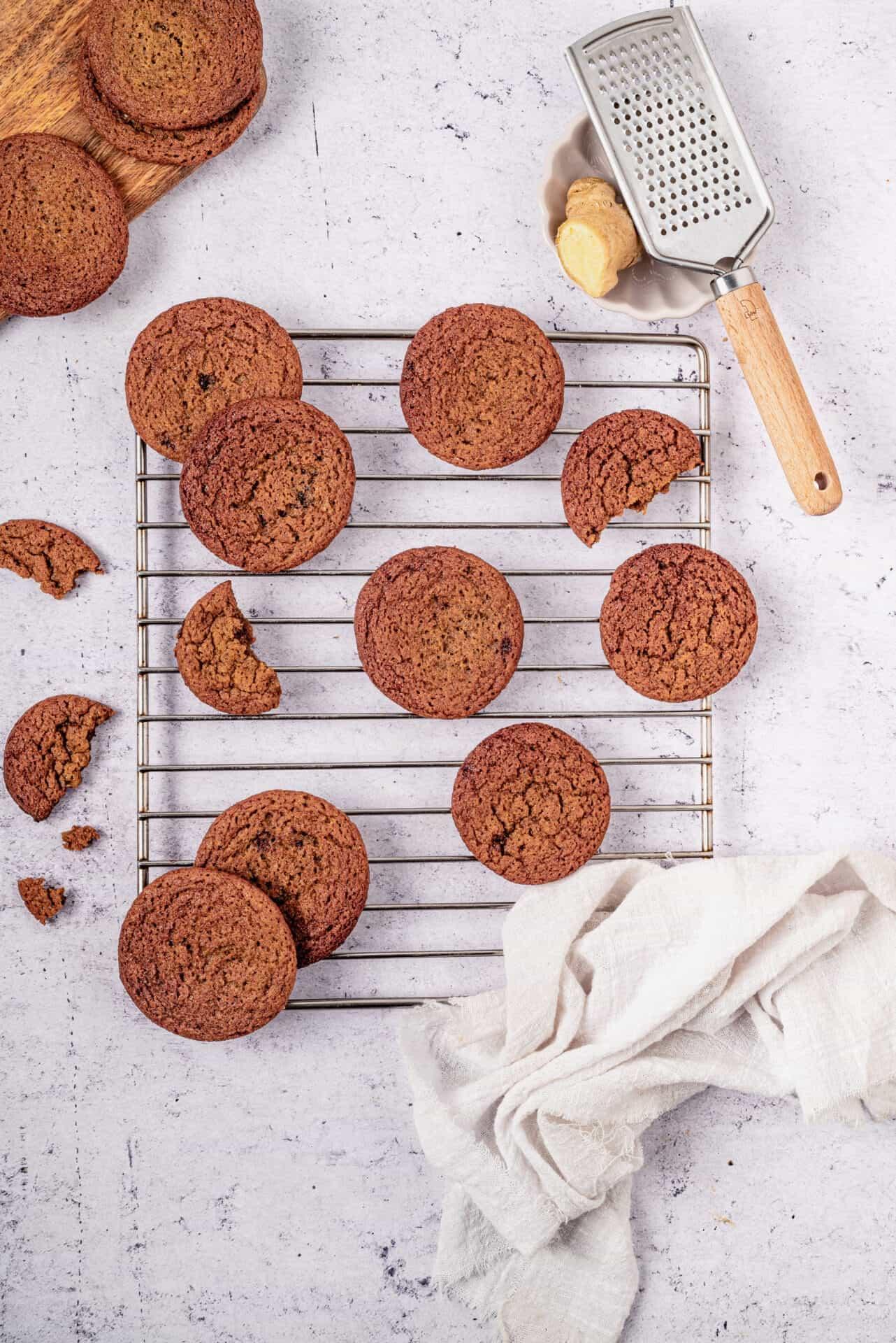 close-up of a hand reaching for a freshly baked molasses cookie on a cooling rack