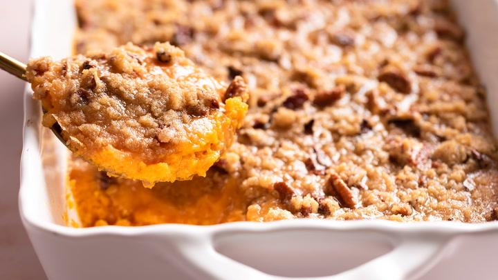 Overhead shot of all ingredients for sweet potato casserole laid out on a kitchen counter: cooked sweet potatoes, butter, brown sugar, milk, vanilla, eggs, pecans, flour.