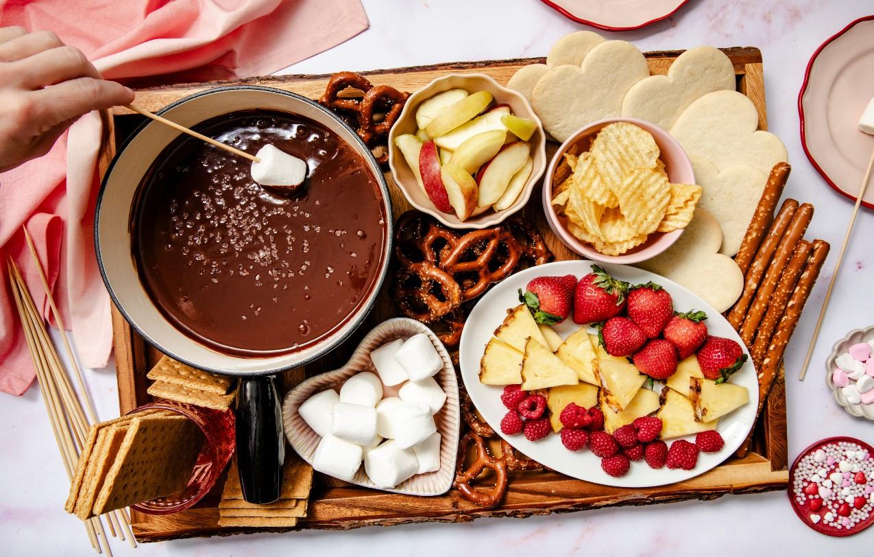 a couple laughing while dipping strawberries into chocolate fondue