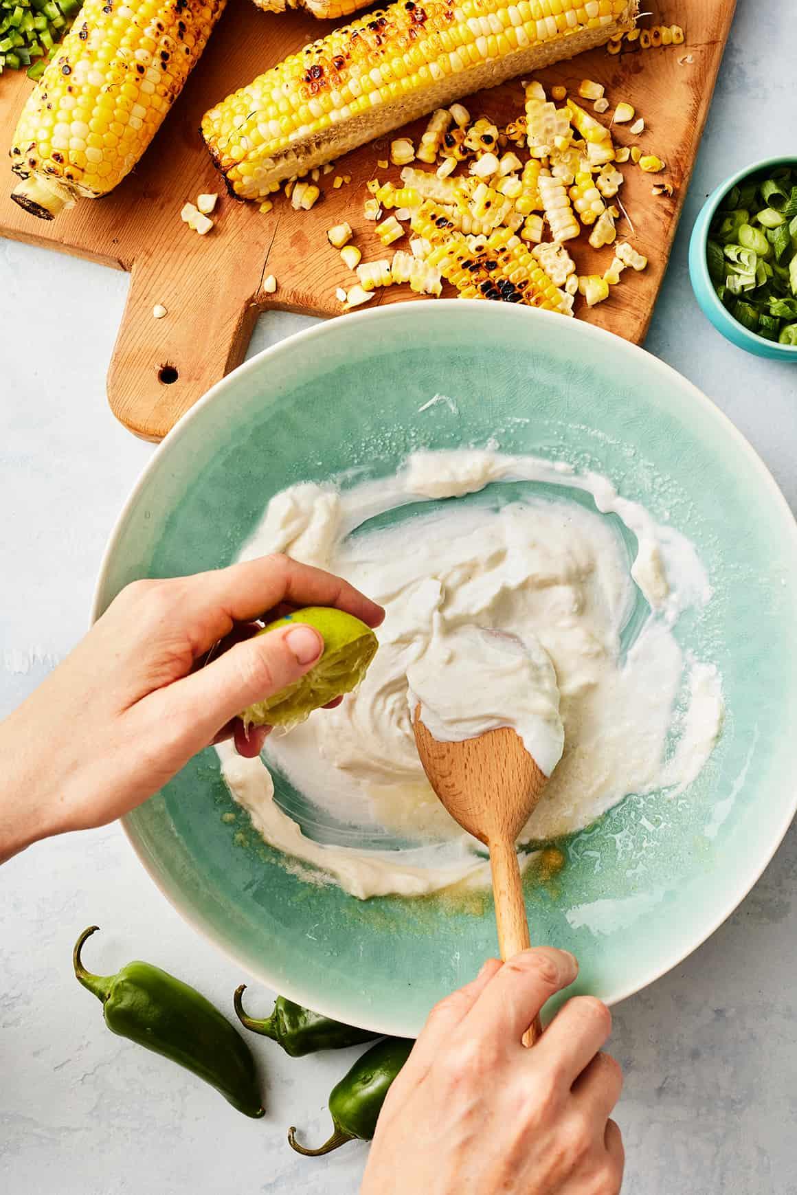 A hand reaching for a tortilla chip to scoop up the Mexican street corn dip