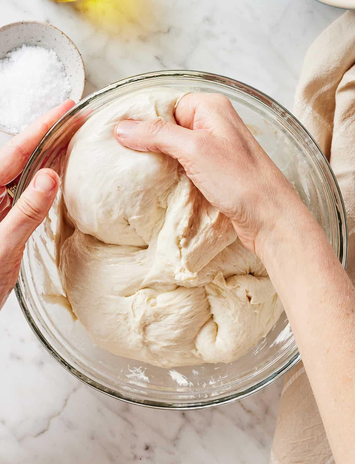 hands kneading focaccia dough