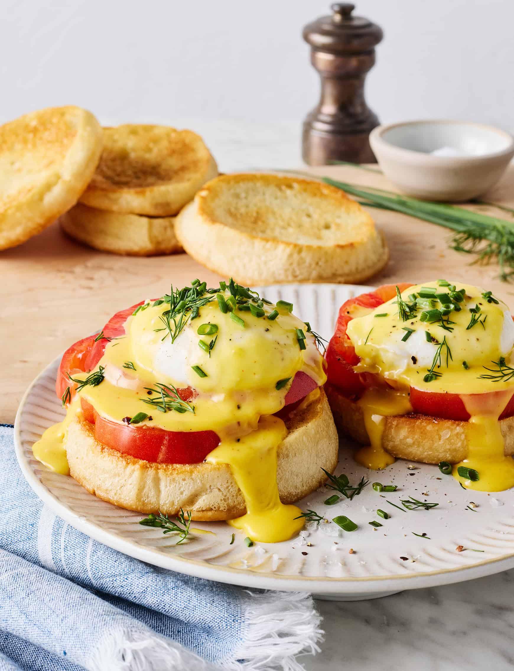 Eggs Benedict on English muffins with tomato slices