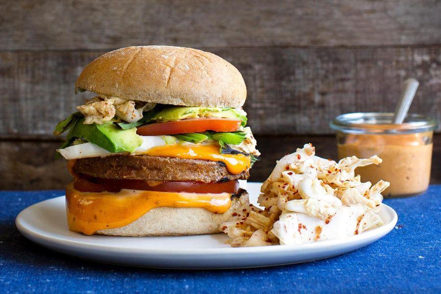 Close-up shot of a kimchi tofu burger being assembled, showcasing the layers of ingredients