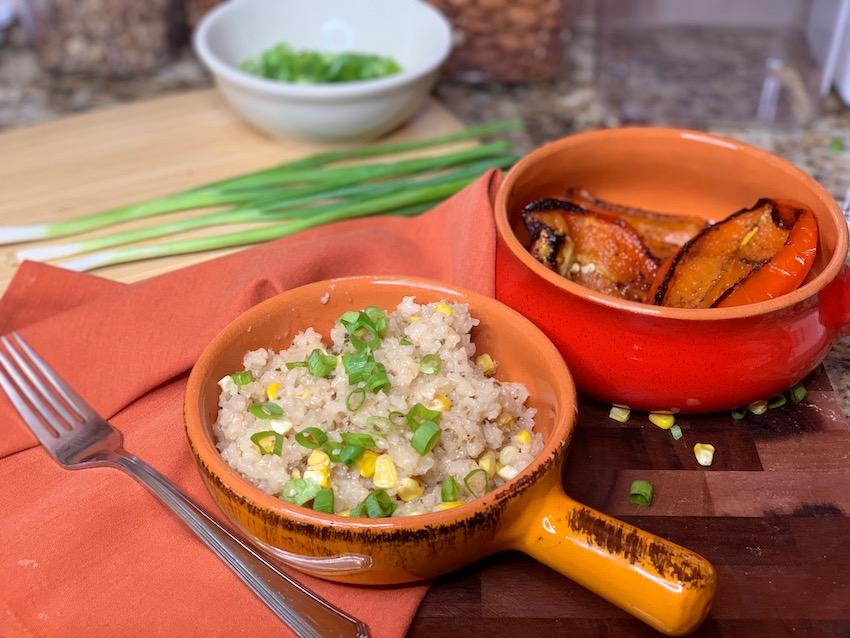 A wider shot of the Grilled Corn Risotto with Roasted Vegetables being served in rustic bowls, alongside a glass of white wine.