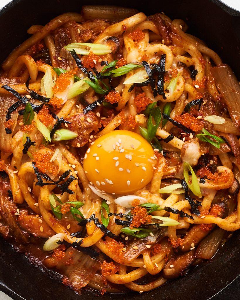 Close up shot of a bowl of Kimchi Udon with seafood, steaming